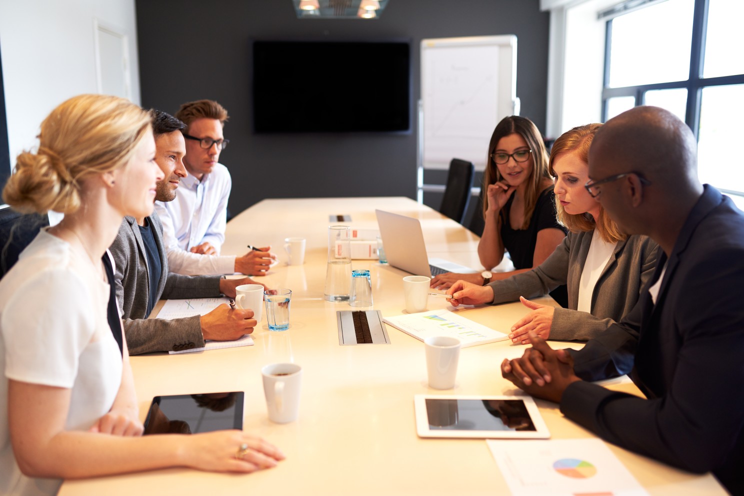 Six coworkers sitting in a conference room having a meeting.