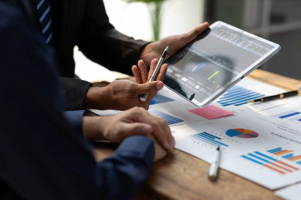 Three coworkers discussing plans written on a glass dry erase board