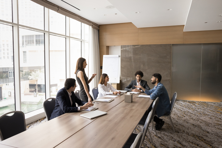 Three coworkers discussing plans written on a glass dry erase board